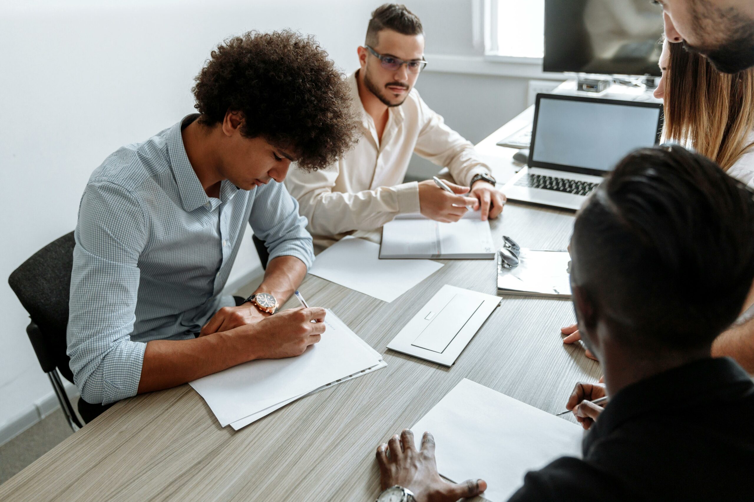 Groupe de collègues en réunion, prenant des notes autour d’une table